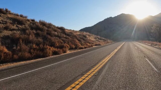 Drive toward morning sun over mountain ridge in Sierra Nevada mtns