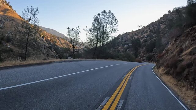 Golden hour sunshine lights rugged scenic river valley, highway POV