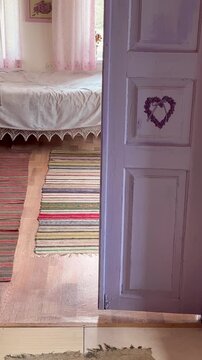 ginger cat jumping off the bed and walking along a handwoven rug in a rustic countryside home. cozy village interior, simple rural lifestyle, authentic domestic scene.