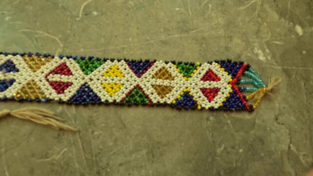 Traditional Amazigh beaded ornament from Morocco featuring geometric diamond patterns and bold colors, showcasing cultural symbolism, craftsmanship, and decorative use in heritage attire.