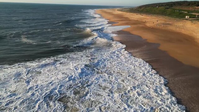 Cinematic Aerial view, Coastal Waters, Blue Horizons, Picturesque Golden Beach Shoreline, Nazare Salgado, Portugal