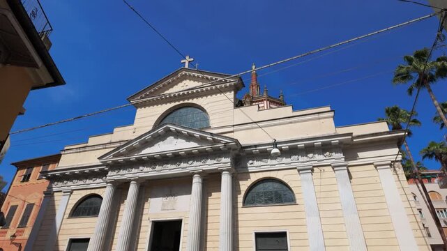 Stunning wide angle footage of the Basilica dei Santi Gervasio e Protasio in Rapallo, Italy, under bright blue skies. Classic neoclassical fa&ccedil;ade, dramatic columns, and warm daylight composition.