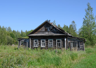 Fototapeta premium Abandoned dilapidated wooden village house by the forest in Karelia