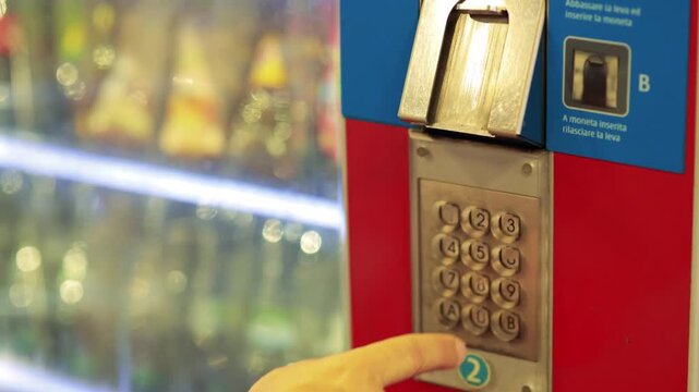 Close up of person using the keypad of a vending machine to make a purchase, selecting item 6 with finger press.