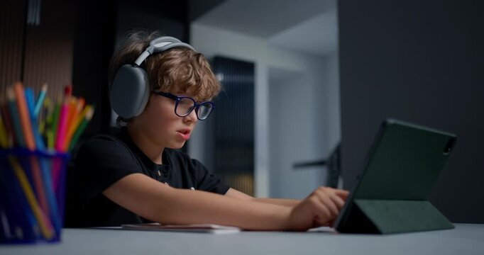 Young Student Deep In Concentration While Practicing Handwriting With Audio Instruction And Bright Supplies