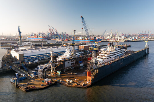 Aerial view of the Port of Hamburg featuring luxury yachts in dry dock with industrial cranes and harbor infrastructure in Hamburg, Hamburg, Germany.