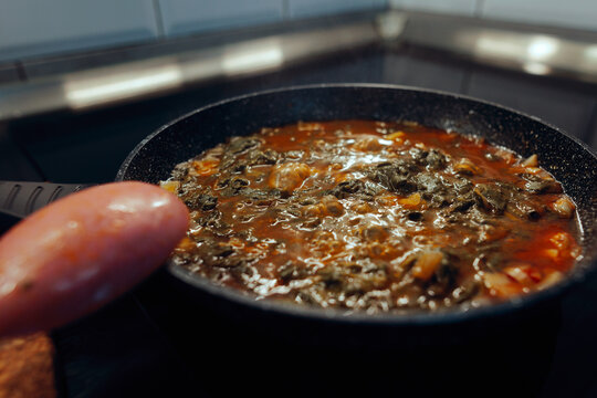 Simmering Patience Dock Stew in Ceramic Skillet 
Vegetable pottage bubbling in a ceramic pan on modern induction hob