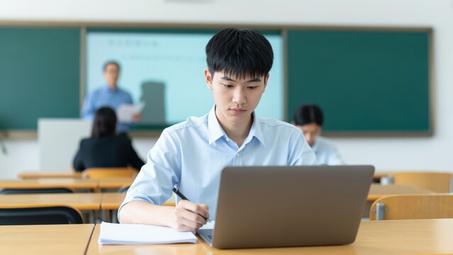 Focused Student: A concentrated student meticulously works on their study with the help of a laptop, writing notes and surrounded by classmates in a vibrant classroom.