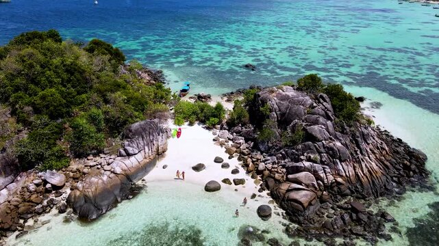 Nestled in the vibrant waters of Koh Lipe Thailand, a secluded beach reveals its natural splendor. Travelers enjoy warm sunshine, clear waters, and stunning rock formations on their relaxing escape.
