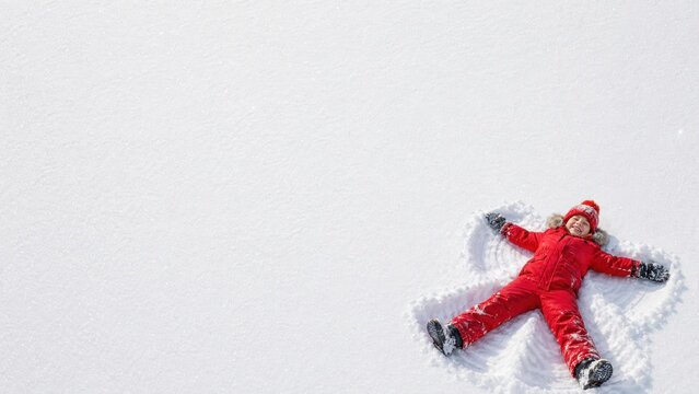 Happy girl making snow angel in winter.