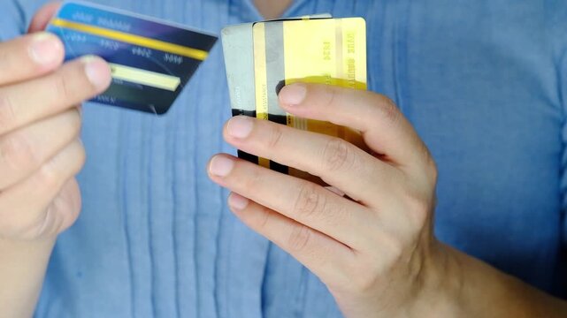 Close up of hand human holding multiple color credit cards, choosing a red card for payment, concept of consumerism, financial management, debt and cashless society and saving money	