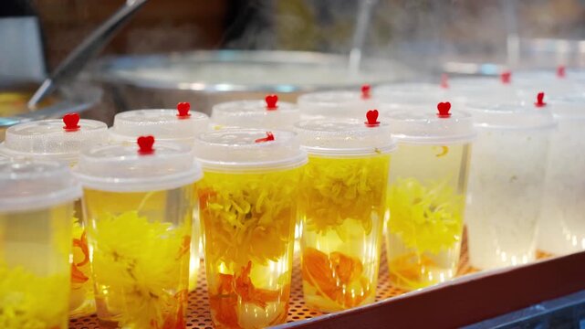 Rows of refreshing flower tea drinks in clear plastic cups at a vibrant street food market