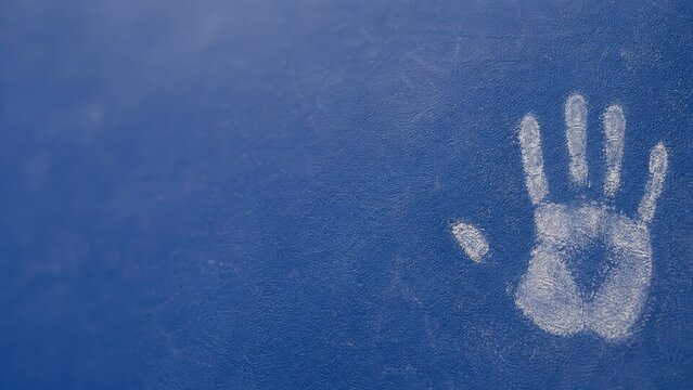White chalk handprint slapped against textured blue rock climbing wall.