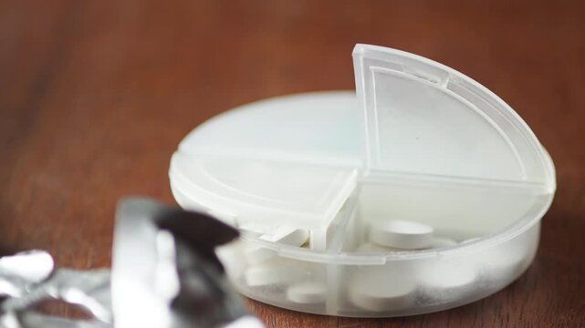 Macro shot capturing a single tablet being placed into a container, emphasizing precision, care, and adherence to a treatment routine.