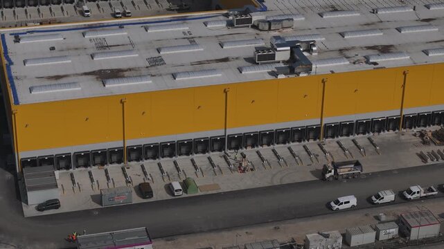 Industrial warehouse and yard operations support large scale distribution, with goods handling and transport flows connected to A1 major motorway corridor in Po Valley, Italy, drone panning