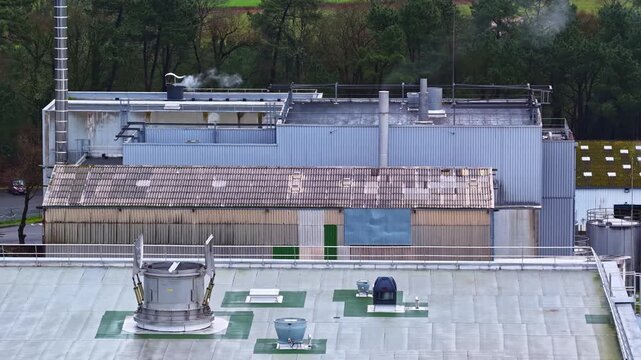 Drone shot of factory rooftop showing chimneys, vents, and weathered metal cladding - France industrial architecture