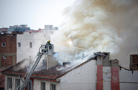 A fireman is fighting to extinguish fire on the roof of a building