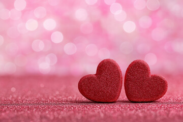 Fototapeta premium two red hearts on a pink glittery background with space for text, creating a bokeh and blurred effect, perfect for valentine's day