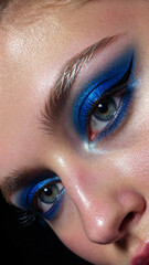 Fototapeta premium model with vibrant sapphire blue eyeshadow blended into icy silver, sharp winged eyeliner, glossy eyelids