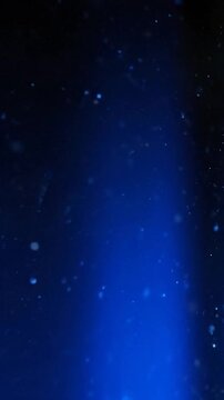 Abstract blue light beam illuminates dark space with floating particles