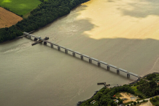Aerial view of Barrow Bridge spanning the River Barrow between lush green fields and dense forests in Wexford, County Wexford, Ireland.