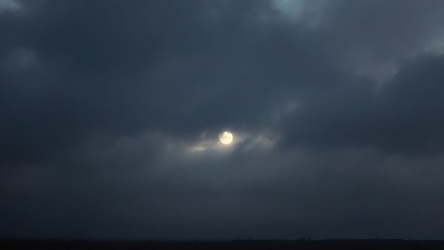 Heavy, overcast sky at dusk with thick gray clouds blocking the sun.
