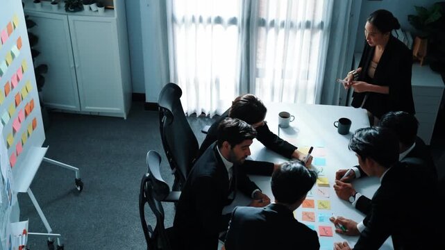 Top view of business people brainstorm idea by using sticky notes while planning marketing strategy at meeting room. Group of diverse team discuss about financial plan. Teamwork concept. Directorate.