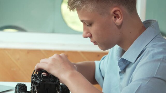 Close up of young student tighten the nut by using screwdriver. Caucasian teenager repairing or fixing car model while inspect robotic machine construction at STEM technology class. Edification