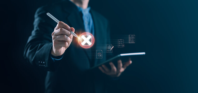Businessman using stylus on tablet to mark rejection with glowing cross icon on digital checklist, representing validation failure, workflow issues, and compliance error in a corporate environment.