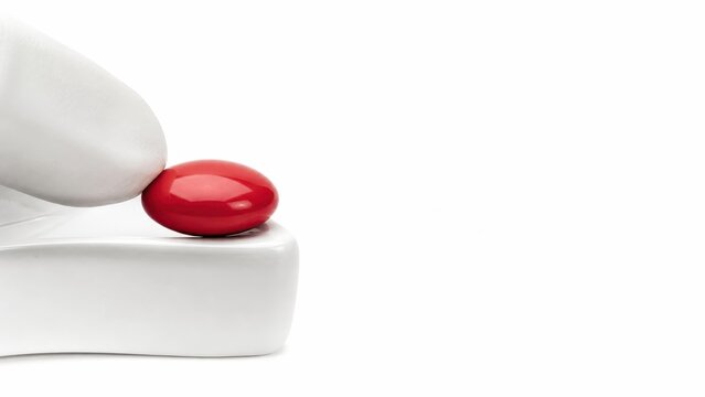 Focusing strictly on the smooth thick edge of a sterile white ceramic sorting dish where a heavily gloved finger guides a single massive solid glossy red pill isolating one object