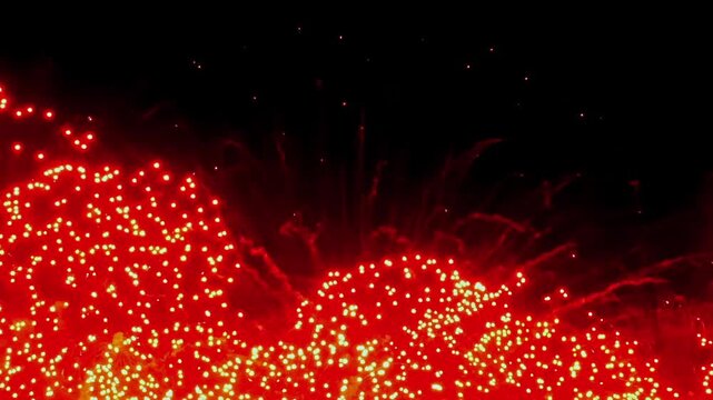 The night sky comes alive with a dazzling array of vibrant red fireworks, creating a breathtaking spectacle that fills the air with excitement during a lively festival celebration.