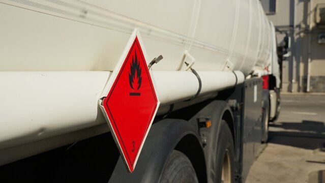 Flammability symbol on the side of a tanker truck stopped at a petrol station