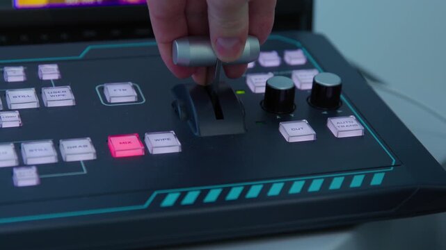 A man zoom in camera angle with electronic device during broadcast. The device is used for controlling the color and brightness of a screen and switching camera angles