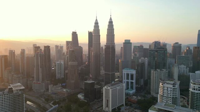 Aerial view of Kuala Lumpur at sunrise featuring the iconic twin towers and modern skyline. Golden hour light over the city highlights urban architecture and city life in Malaysia.