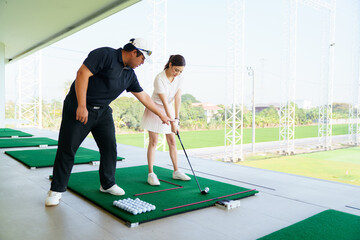Naklejka premium Professional golf coach adjusting posture for female student