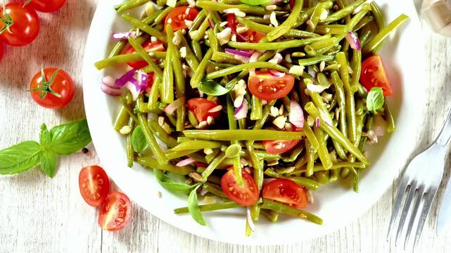 fresh healthy green bean salad with cherry tomatoes and onions in a white bowl on a rustic wooden table
