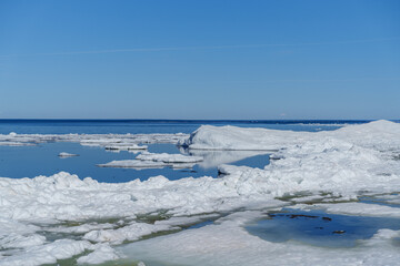 Obraz premium Arctic landscape with melting ice floes in the blue ocean under a clear sky. A beautiful polar landscape featuring chunks of melting ice and white floes drifting in the deep blue sea water.