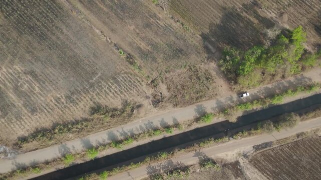 Aerial drone footage of a pickup truck driving on a rural road through countryside landscape. Scenic view of travel, transportation, and freedom in nature