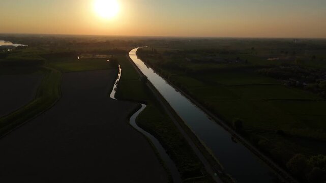 Canale Milano Cremona Po near Spinadesco Lombardy Italy running parallel to River across cultivated fields in Pianura Padana Po Valley sunset light with spring conditions, smooth drone tilt down shot