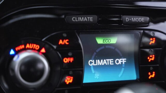 a vehicle center console featuring a digital screen with "CLIMATE OFF" in Eco mode. Red backlit buttons and modern interface dials are visible in a sleek black interior.