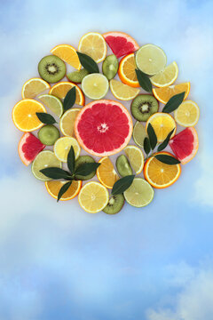 Fantasy fresh citrus fruit and leaf abstract food art design. Healthy summer tropical colorful theme in circle shape on blue sky cloud background.