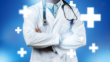 Doctor stands with arms crossed in a medical setting with blue background and plus signs © fotofabrika
