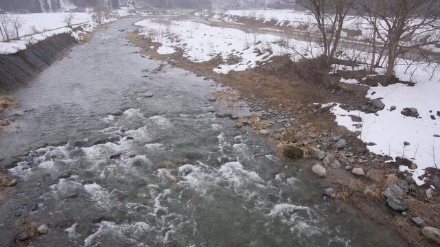 福島県南会津町の伊南川、雪が降る山里を流れる冬の河川と残雪の河原4K映像