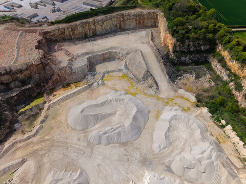 Aerial view of Marshalls Maltby quarry showing large piles of aggregates and excavated limestone faces under bright daylight in Maltby, England, United Kingdom.