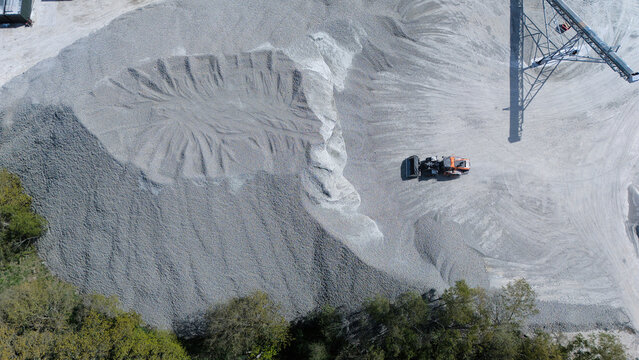 Aerial view of the Foamed Glass Industrial Factory with a heavy loader vehicle working on a large pile of grey aggregate material and industrial machinery in Great Heck, England, United Kingdom.