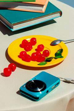 Colorful still life with cherry on plate and camera