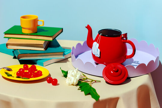 Colorful modern still life with red teapot tea and book on table