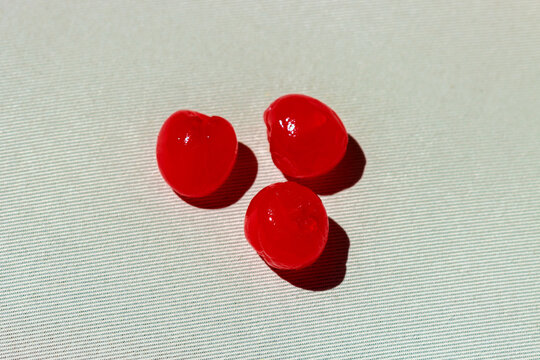 Three bright red candied cherries on white textured background