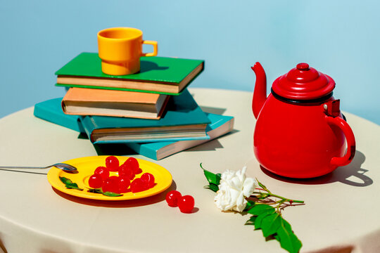 Colorful still life with teapot books and cherries on a table
