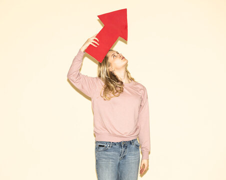 Woman looking at red paper arrow pointing up for strategy and direction